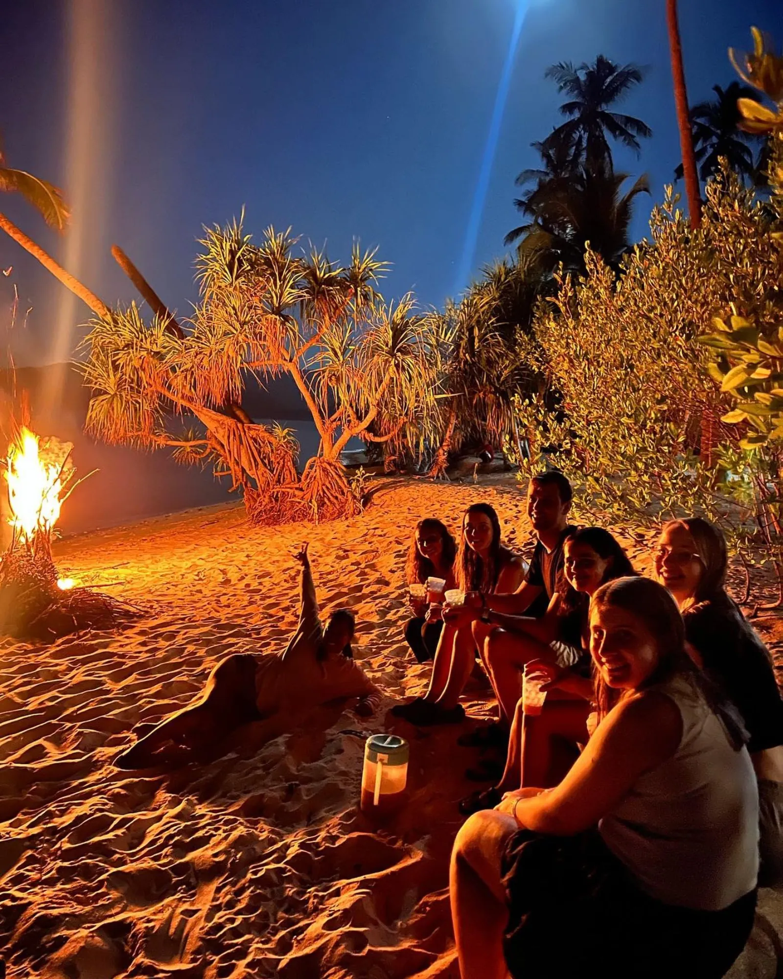 Travellers around a bonfire on the beach at night