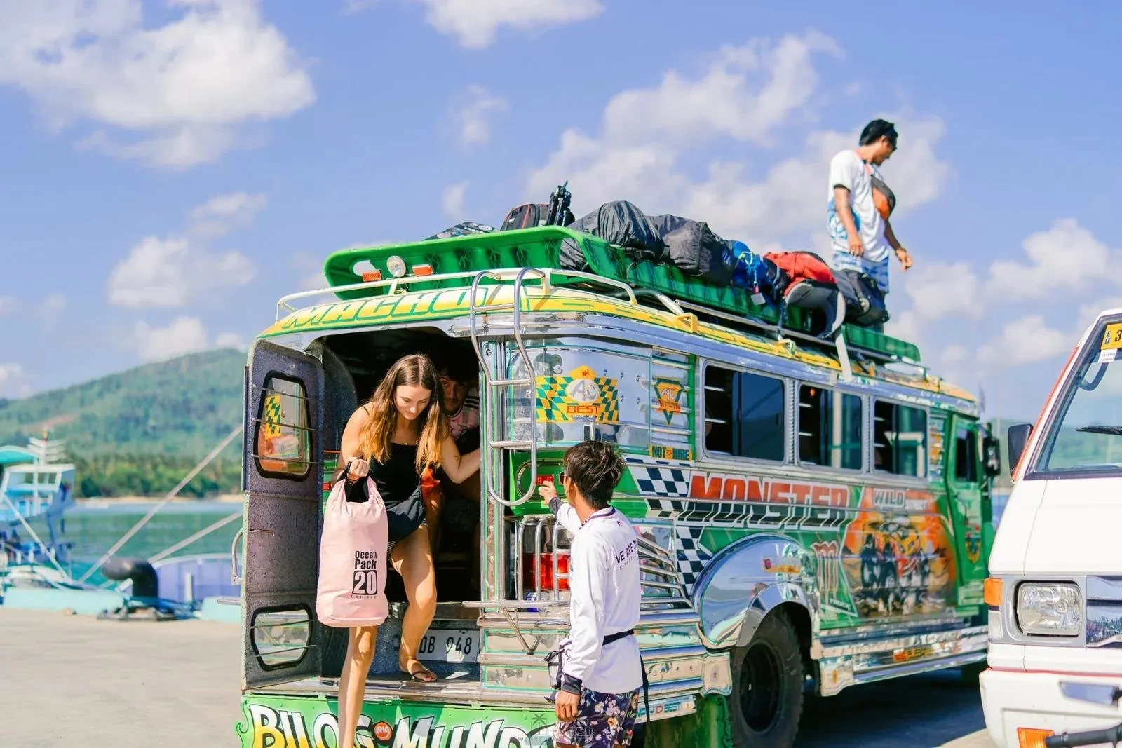 Travellers boarding a painted jeepney transfer with luggage on the roof