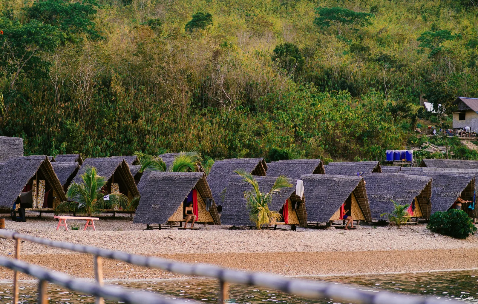 A row of thatched native huts along the beach at an island camp