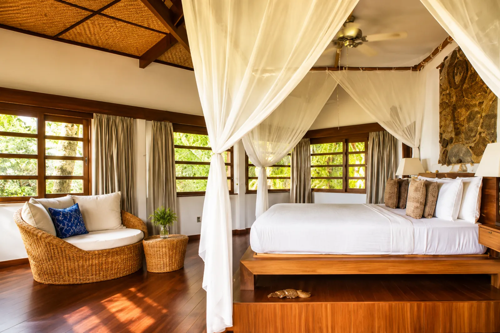 A resort bedroom with a canopy bed and wooden floors
