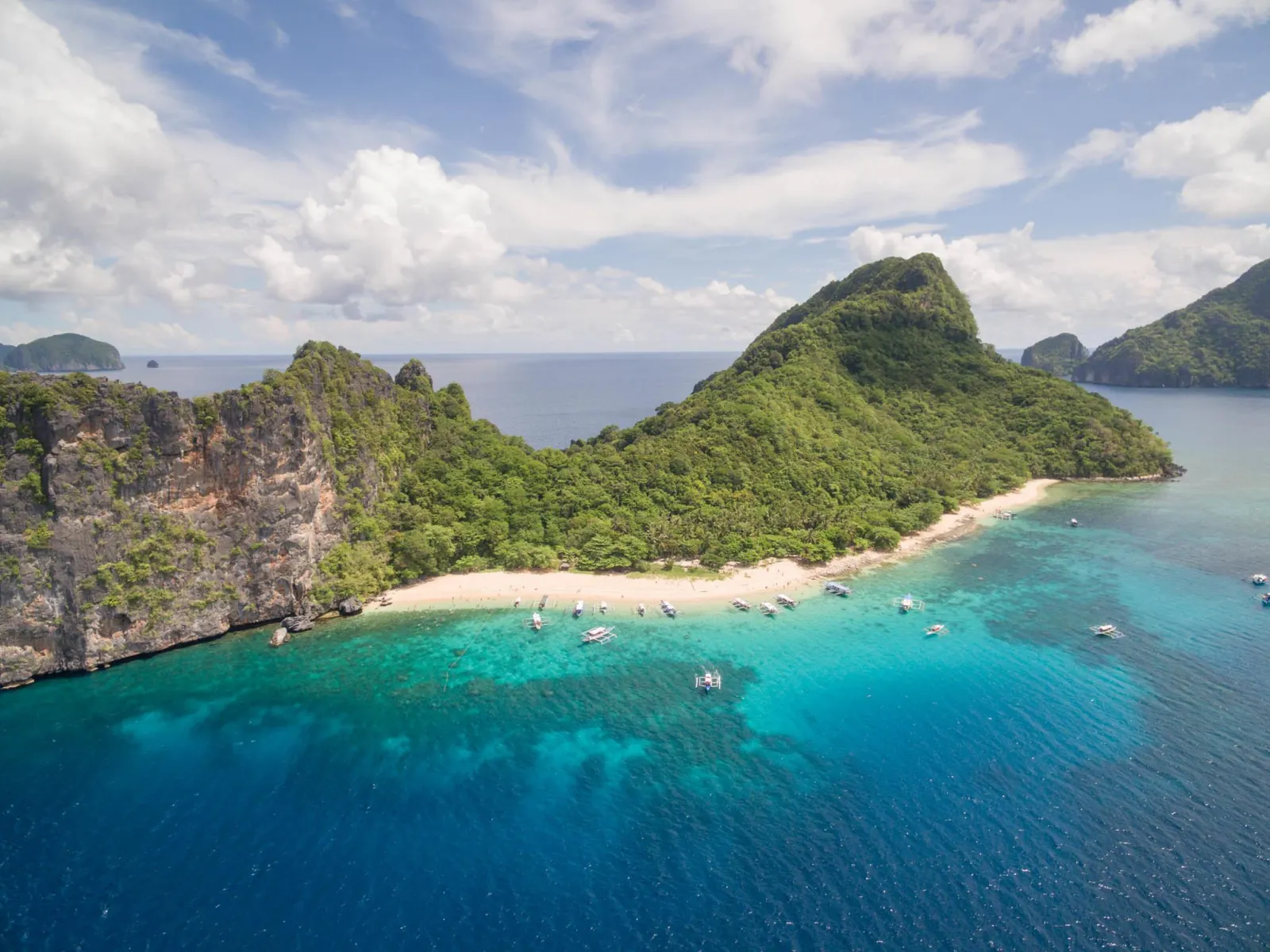 Aerial view of an island with a white beach and turquoise reef off El Nido
