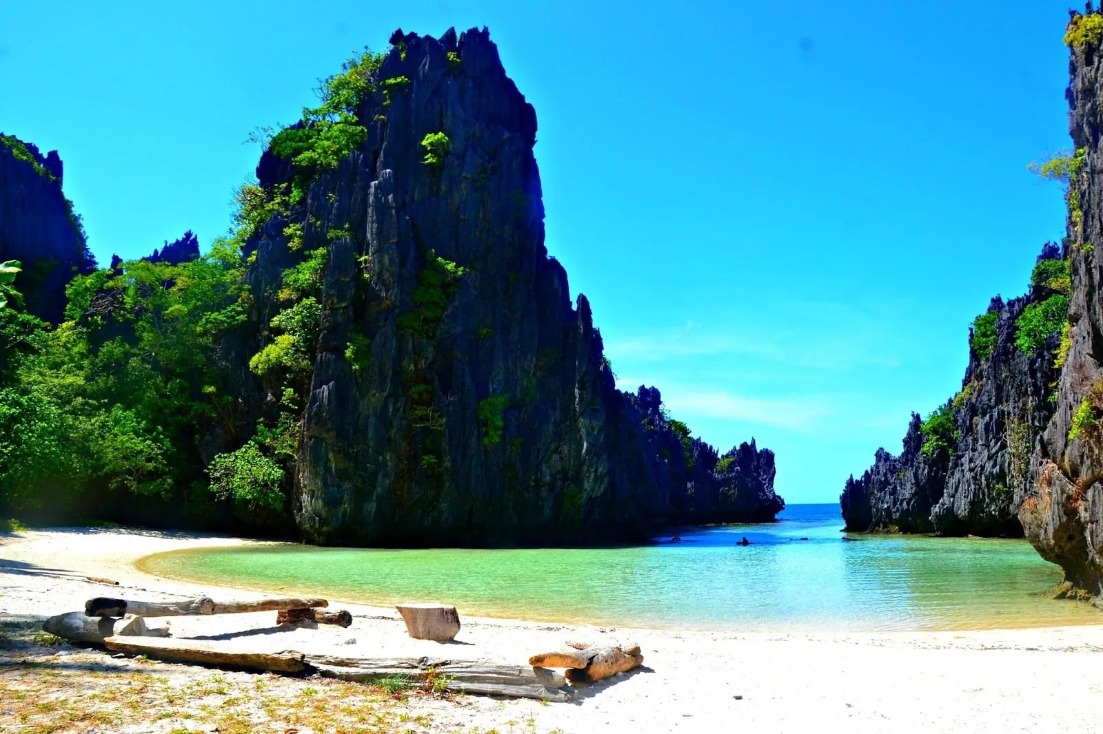 A small white beach between towering limestone cliffs