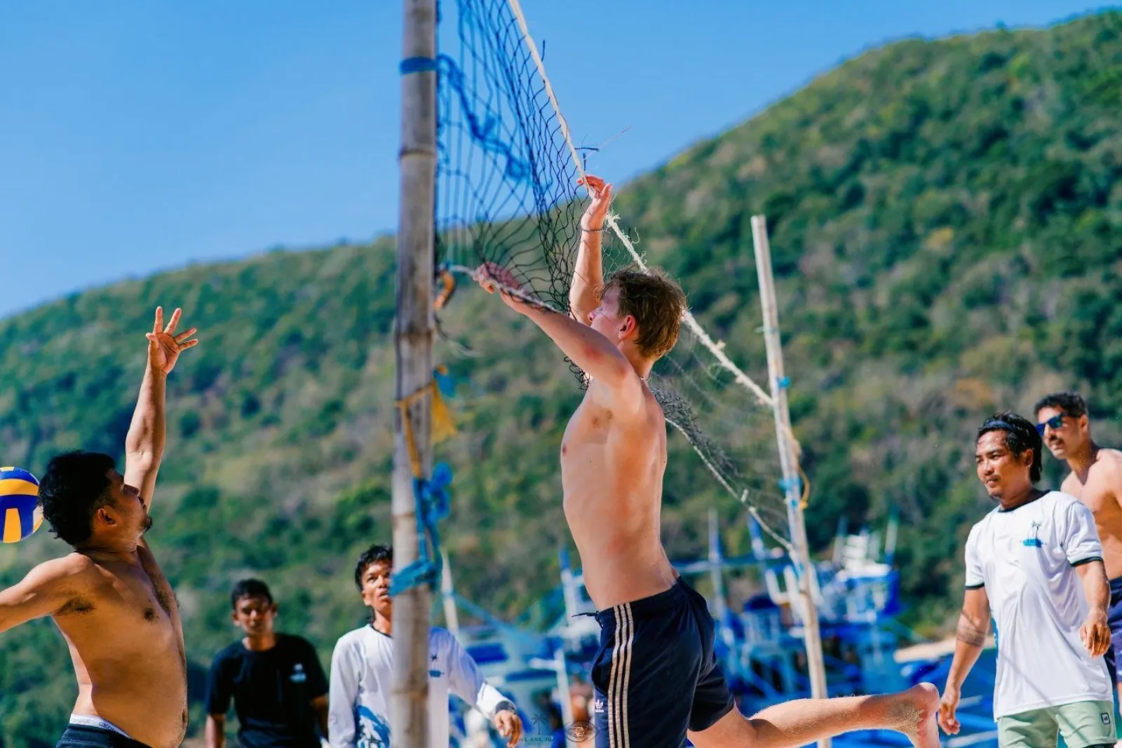 Travellers playing beach volleyball at an island basecamp