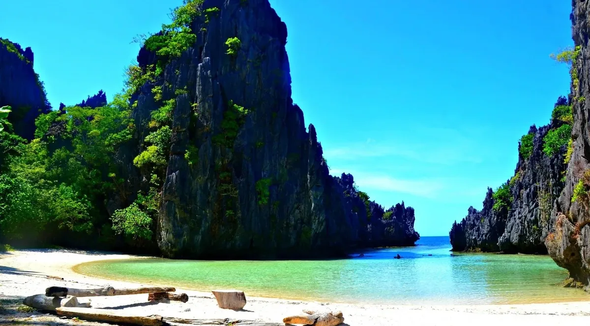 Small white-sand beach between towering limestone cliffs in El Nido