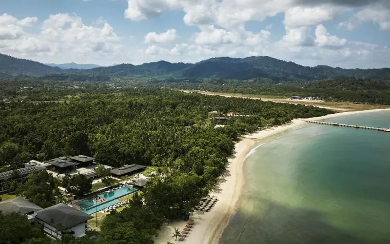 Aerial view of Seda Lio's pool and low buildings behind the long curve of Lio Beach