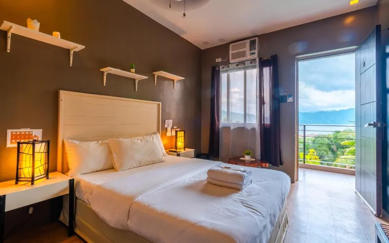 Double room at The Ridge Coron with an open balcony door looking out to green hills