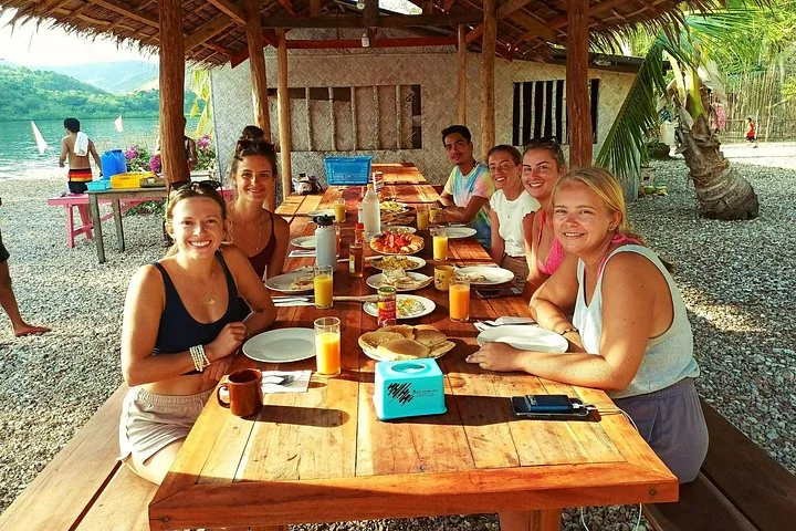 Travellers at breakfast at a wooden table in a beach hut