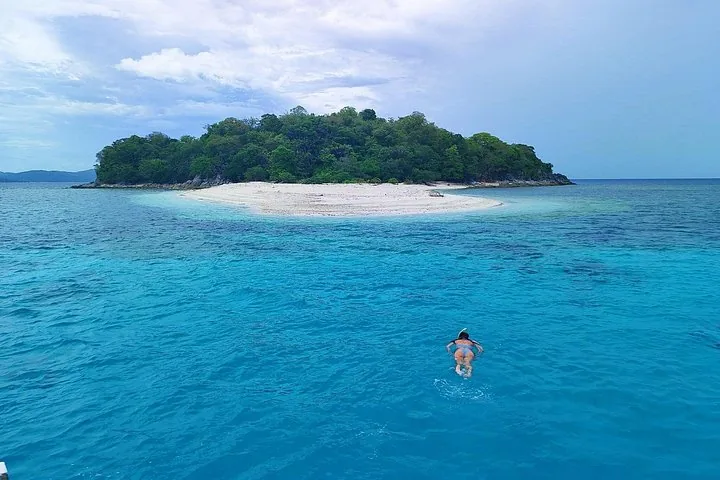 A snorkeller swimming toward a small island with a white beach