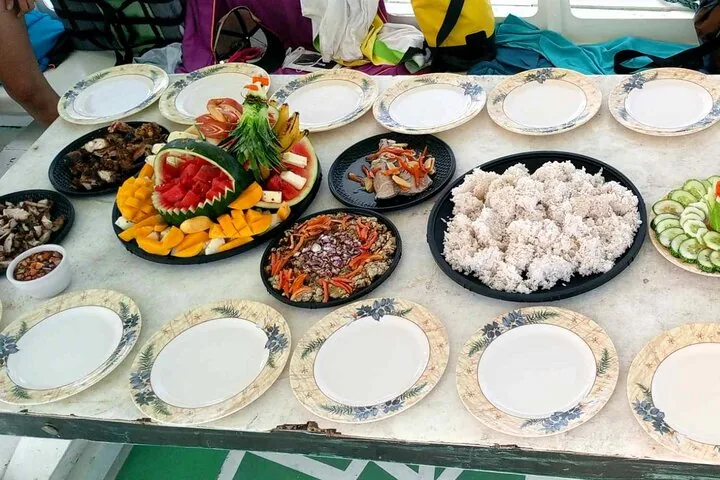 Platters of grilled fish, rice and fruit laid out for a shared meal
