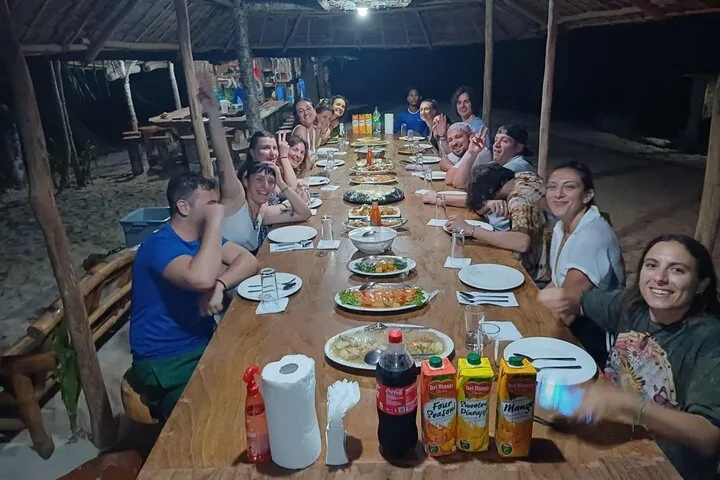 An evening group dinner at a long table at the island camp